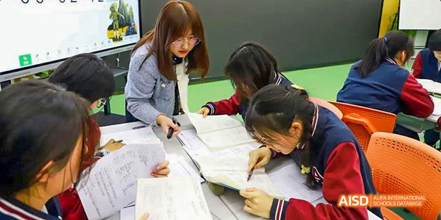 Hefei Thomas School students collaborating while studying from a book at a table.