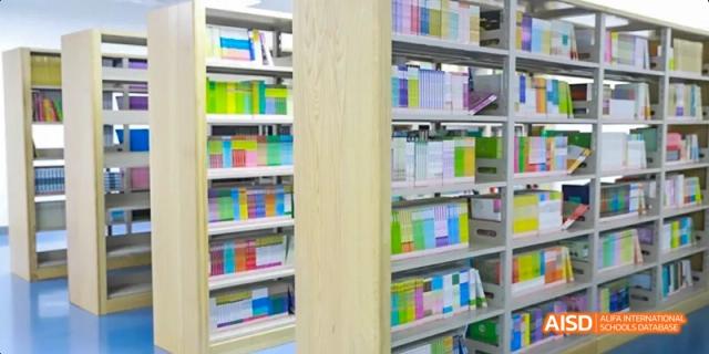 An interior view of the library at Hefei Thomas School, showcasing rows of colorful books on shelves.