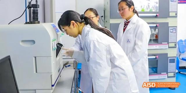 Two Hefei Thomas School students in lab coats conducting a scientific experiment together.