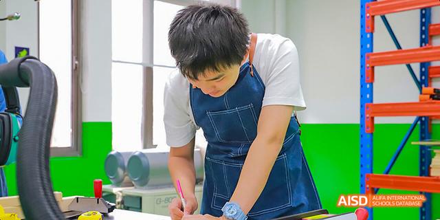 A Hefei Thomas School student in a kitchen, writing notes while preparing to cook.