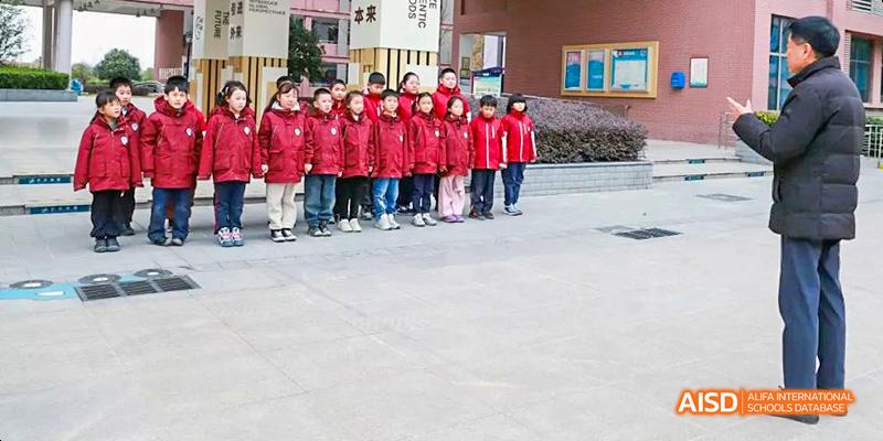 A line of students in red jackets standing outside for a group photo at Hefei Thomas School.