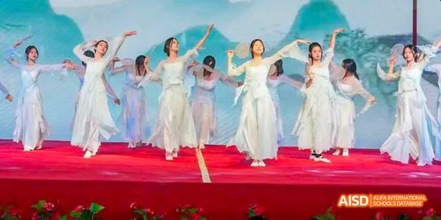 Hefei Thomas School students performing a traditional Chinese fan dance on stage.