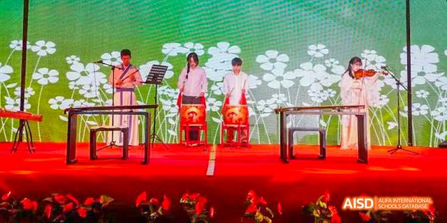 Hefei Thomas School students playing drums during a live performance on stage.