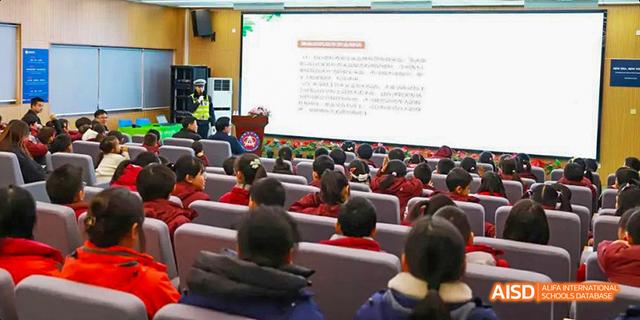 Hefei Thomas School students sitting in an assembly hall, listening to a presentation displayed on a large screen.