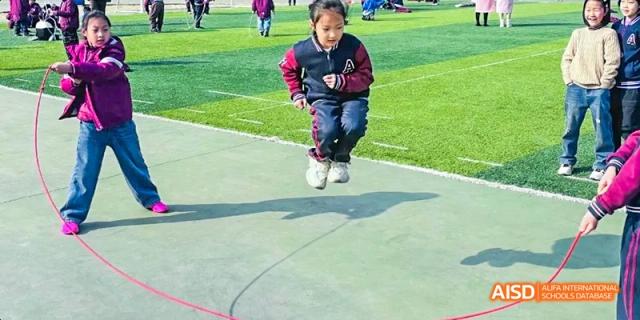 A Hefei Thomas School student doing a jump squat on an outdoor basketball court.