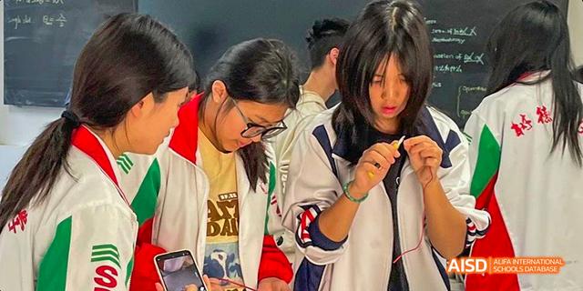 A group of students from the International Department of Chengdu Shude High School working closely together, focused on a small task.