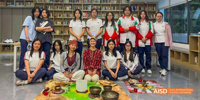 A group of students and a teacher from the International Department of Chengdu Shude High School participating in a cultural activity, sitting around traditional objects.
