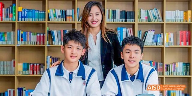 A teacher posing with two male students from the International Department of Chengdu Shude High School in front of a library shelf.