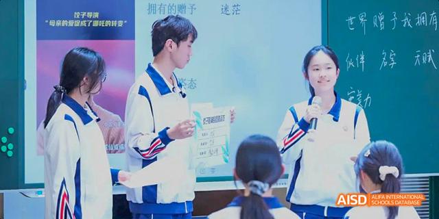 A male student from the International Department of Chengdu Shude High School presenting his work and holding an award certificate to peers.