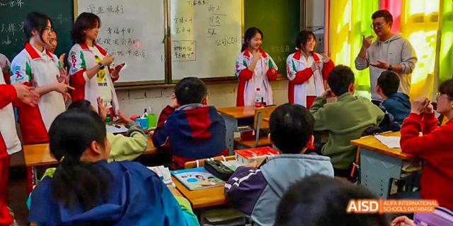 A classroom scene with a female student from the International Department of Chengdu Shude High School giving a presentation or answering a question in front of a whiteboard.