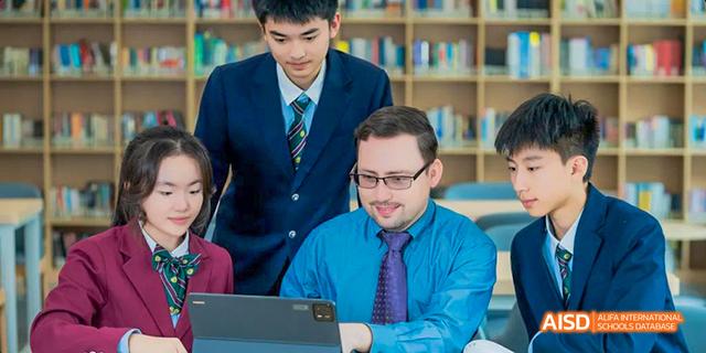 A teacher and an international faculty member collaborating on a computer with a student from the International Department of Chengdu Shude High School standing behind them.