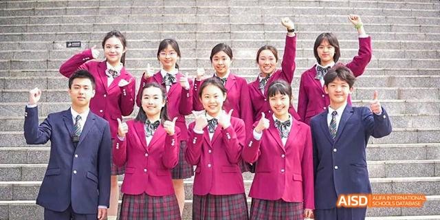 A group of smiling female students from the International Department of Chengdu Shude High School wearing red blazers and checkered skirts, celebrating an event.