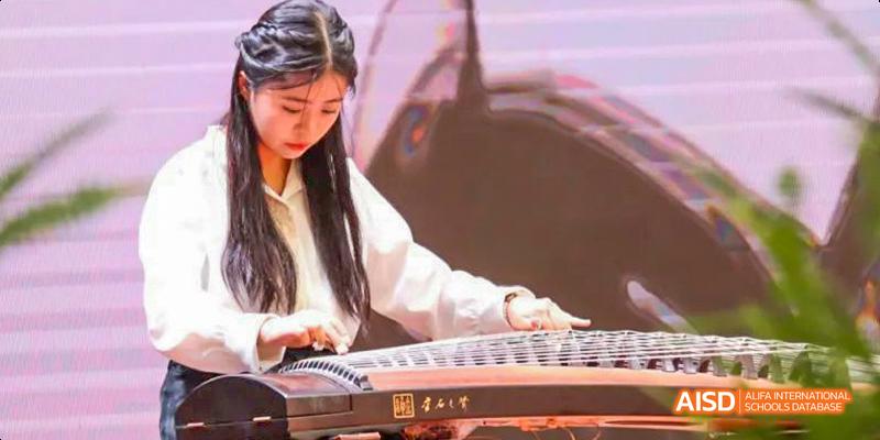 A close-up of a student from the International Department of Chengdu Shude High School skillfully playing the traditional Chinese instrument, the guzheng (zither).