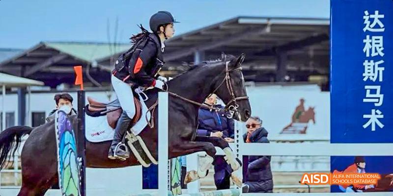 A student from the International Department of Chengdu Shude High School participating in an equestrian competition, jumping a fence on a dark horse.