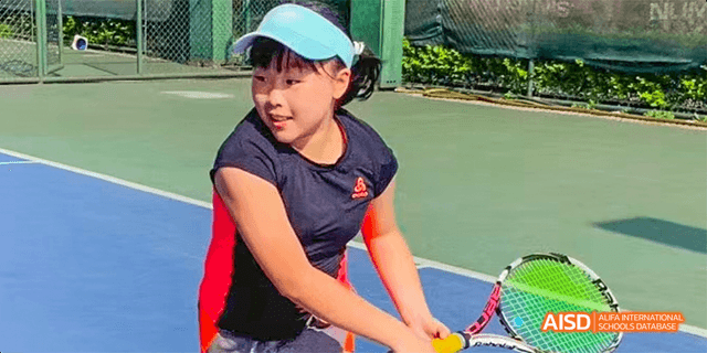 A close-up action shot of a student from the International Department of Chengdu Shude High School playing tennis on an outdoor court.