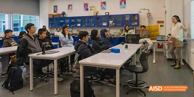 A classroom of students from the International School of Beijing sits at tables and works on their projects.