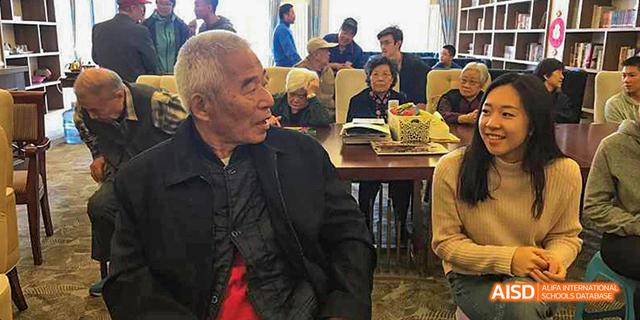 A group of parents and students from the International School of Beijing are shown talking together in a relaxed setting.
