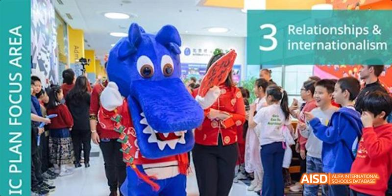 Students from the International School of Beijing pose for a photo with a person in a dragon mascot costume.