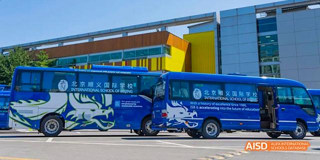 The side of a blue school bus is shown with the International School of Beijing logo.
