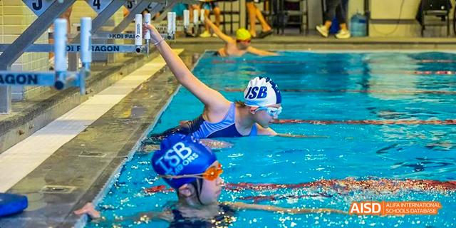A student from the International School of Beijing performs a backflip into a swimming pool.