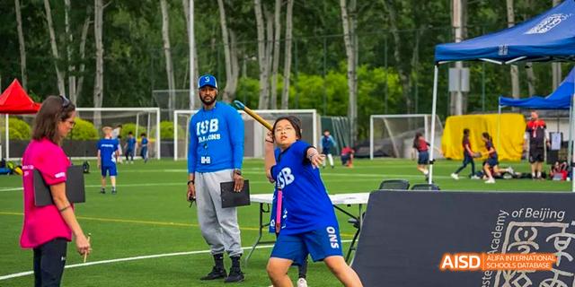 A student from the International School of Beijing looks at the camera while kicking a soccer ball.