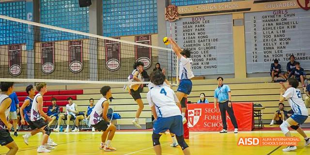 Two students from the International School of Beijing jump to hit the ball during a volleyball game.