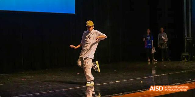 A student from the International School of Beijing performs a dance routine on a stage.