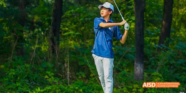 A student from the International School of Beijing plays golf on a green course.