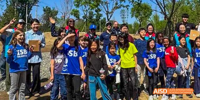 Students and teachers from the International School of Beijing pose for a group photo outdoors.