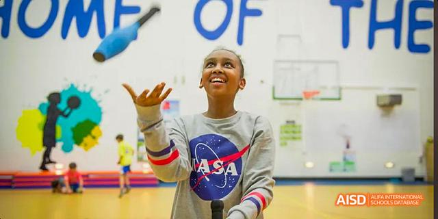 A student from the International School of Beijing smiles while performing a trick with a ball.