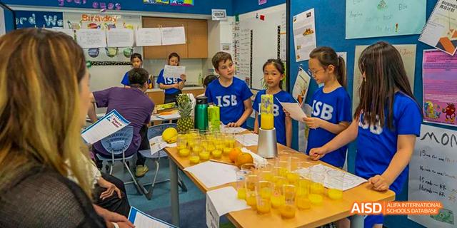 A group of students from the International School of Beijing work together on a cooking or food preparation activity.