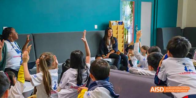 A young student from the International School of Beijing raises their hand in a classroom.
