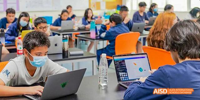 International School of Dongguan students collaborating and discussing a project while working at tables in a bright classroom.