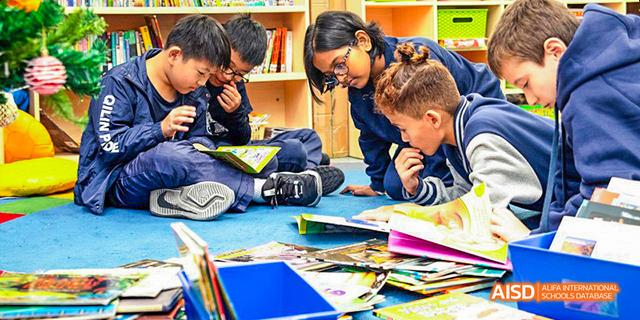 Close-up of International School of Dongguan students working together on a colorful hands-on project or assignment using books and materials.