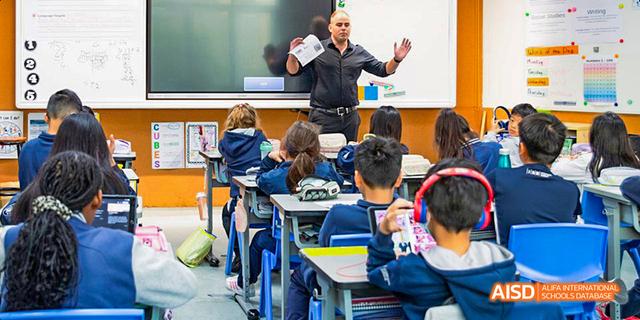 An International School of Dongguan teacher standing in front of the class and engaging with students seated at their desks.
