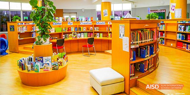 Bright and inviting interior of the International School of Dongguan library, showing bookshelves filled with books and seating areas.