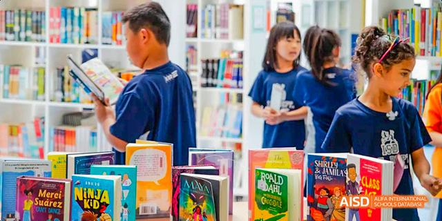Close-up of an International School of Dongguan student looking at a selection of colorful books in the school library.