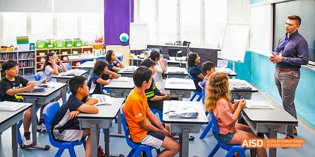 Students working actively at their desks in a busy, modern International School of Dongguan classroom.