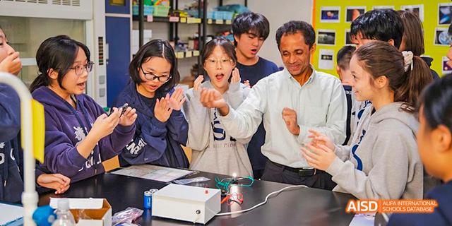 International School of Dongguan students and a teacher reacting enthusiastically to a science experiment or demonstration.