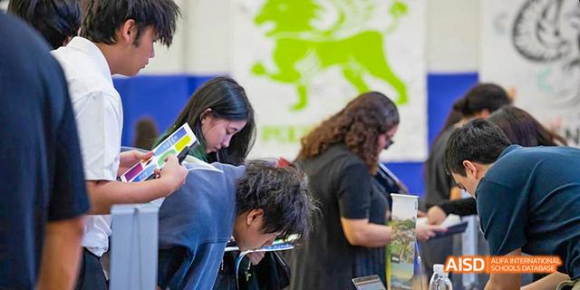 International School of Dongguan students working closely together and looking down at materials during a group project or learning activity.