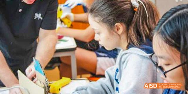 International School of Dongguan student focusing on connecting wires while working on an electronics or circuit building project.