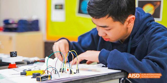 International School of Dongguan student carefully setting up a breadboard and connecting components for a STEM project.