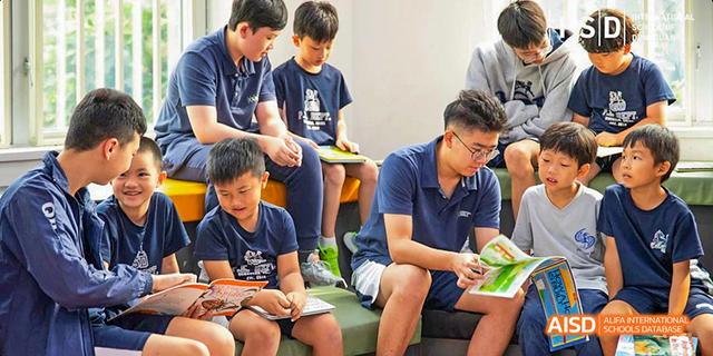 International School of Dongguan students sitting together, with one looking focused while reading a book in a group setting.