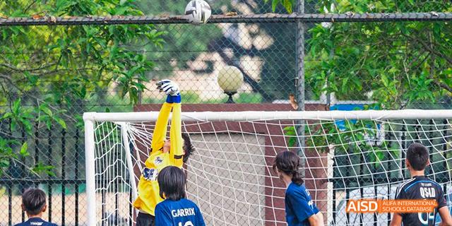 International School of Dongguan student attempting to kick a ball into a goal during a soccer or sports training session.
