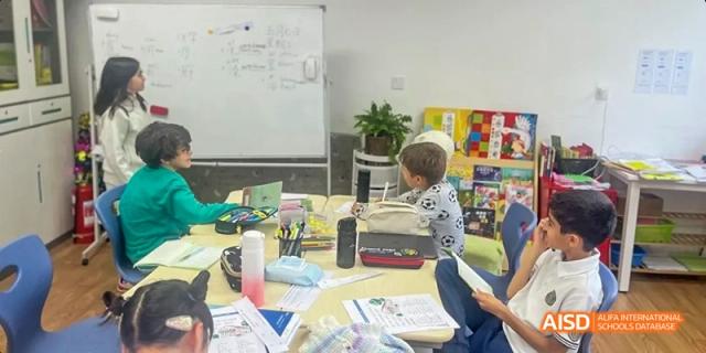 Students from JPED Academy, sitting in a classroom with a variety of art supplies on the desks.