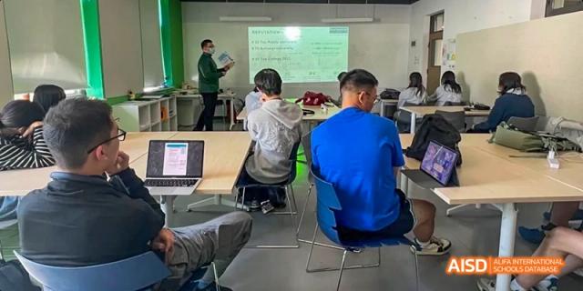 Students from JPED Academy, sitting at desks and using laptops in a classroom.