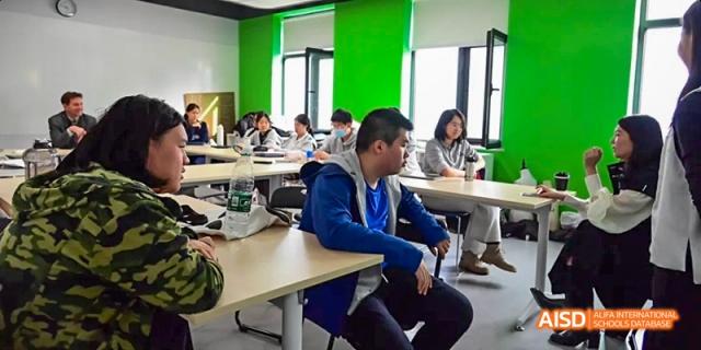 Students from JPED Academy, sitting at tables and working together on an activity in a bright classroom.