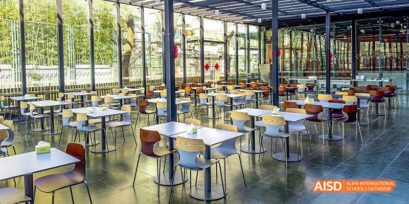 An interior view of the cafeteria at JPED Academy, with multiple tables and chairs.