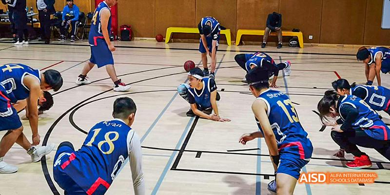 Students from JPED Academy, playing basketball on an indoor court during a game.