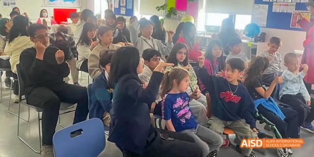 A group of students from JPED Academy, sitting in an auditorium and listening to a speaker.